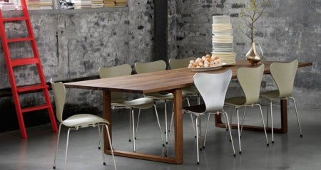 The Essay Table from Fritz Hansen, shown here in walnut, combines with a mix of Series 7 chairs in olive grey and polished aluminum. The table is available in 4 lengths, oak, black oak and walnut.