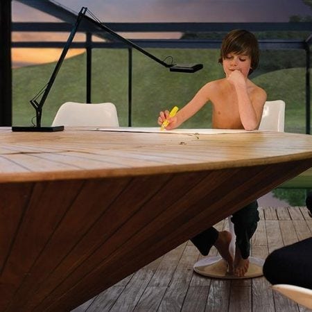 Under a summer sky this young man works under a Flos Kelvin Desk Lamp. Available as a table, wall or floor lamp, the series of Flos Kelvin Lamps provide direct lighting, with a pantograph arm and an adjustable head.