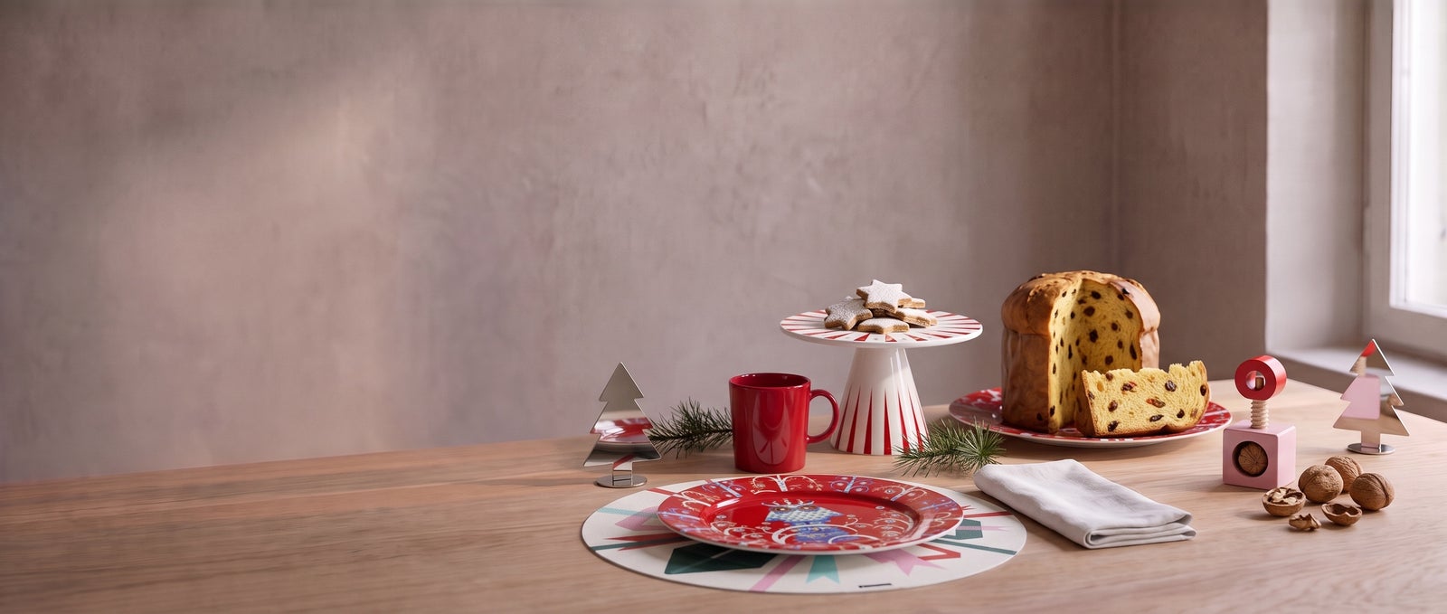 A holiday table with an Iittala Taika plate on a Chilewich Bow placemat, a Teema mug, the Alessi Delight cake stand and panettone plate, a Twergi nutcracker and Barkplace place markers
